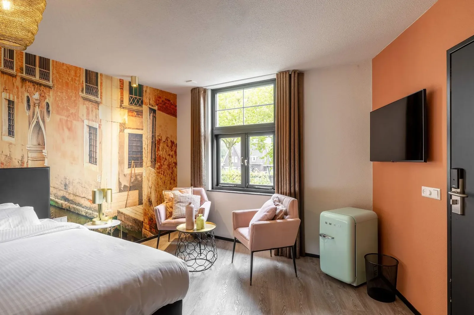 Room at Boutique Hotel de Statie with a large bed, pink armchairs and a wall-mounted IPTV television